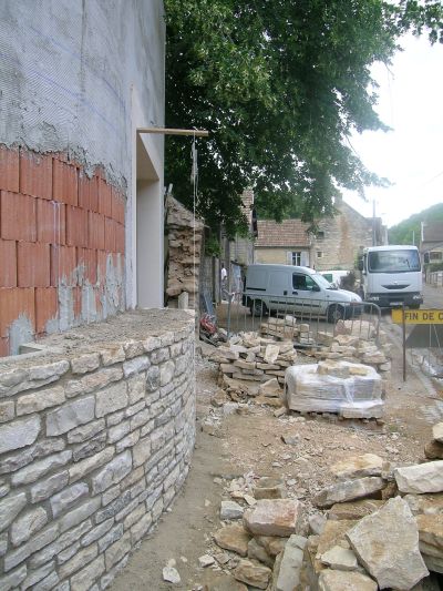 Mur courbe du nouveau bâtiment sur le domaine public, prolongement du mur de clôture en pierre - Patrice Migairou Architecte d'intérieur CFAI